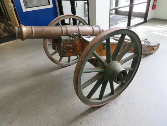 Bronze cannon on wood and metal wheels.