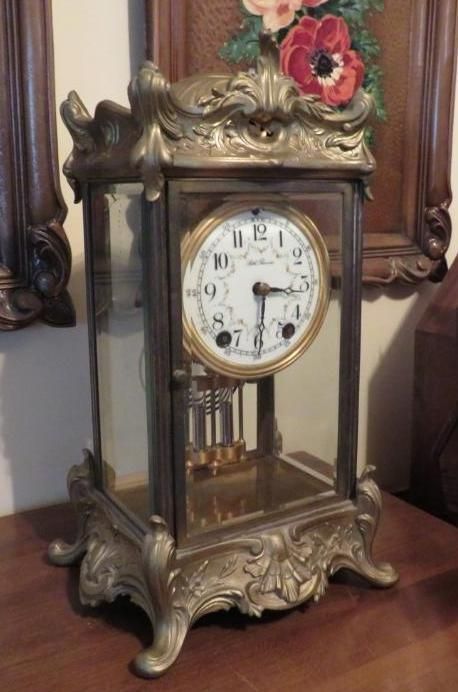 Antique brass and glass clock with a white face, on a wooden table.