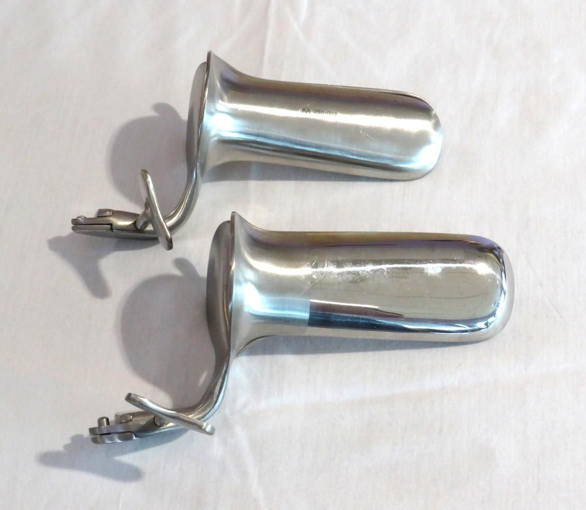 Two shiny, chrome medical devices lying on a white surface, angled slightly different.