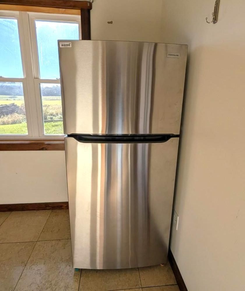 Stainless steel refrigerator in a kitchen near a window.