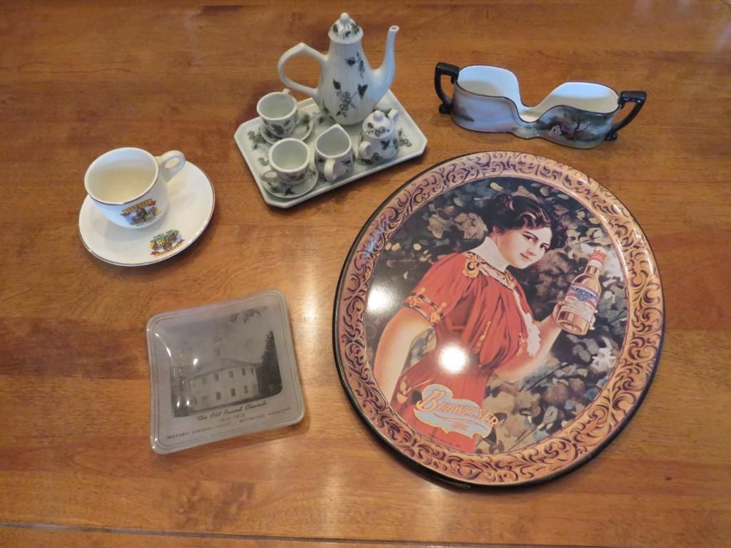 Teapot, cups, and a decorative plate with an image of a woman, all on a wooden table.