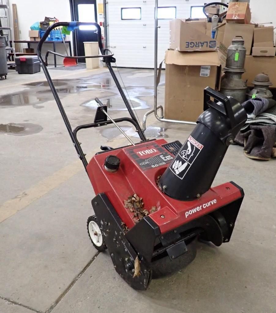 Red Toro Power Clear snowblower with black chute in a garage.