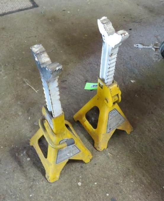 Two yellow car jack stands on a concrete surface.