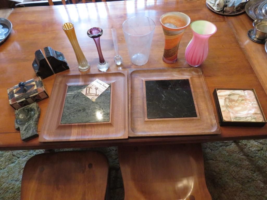 Various decorative glass vases and marble-topped square coasters on a wooden table.