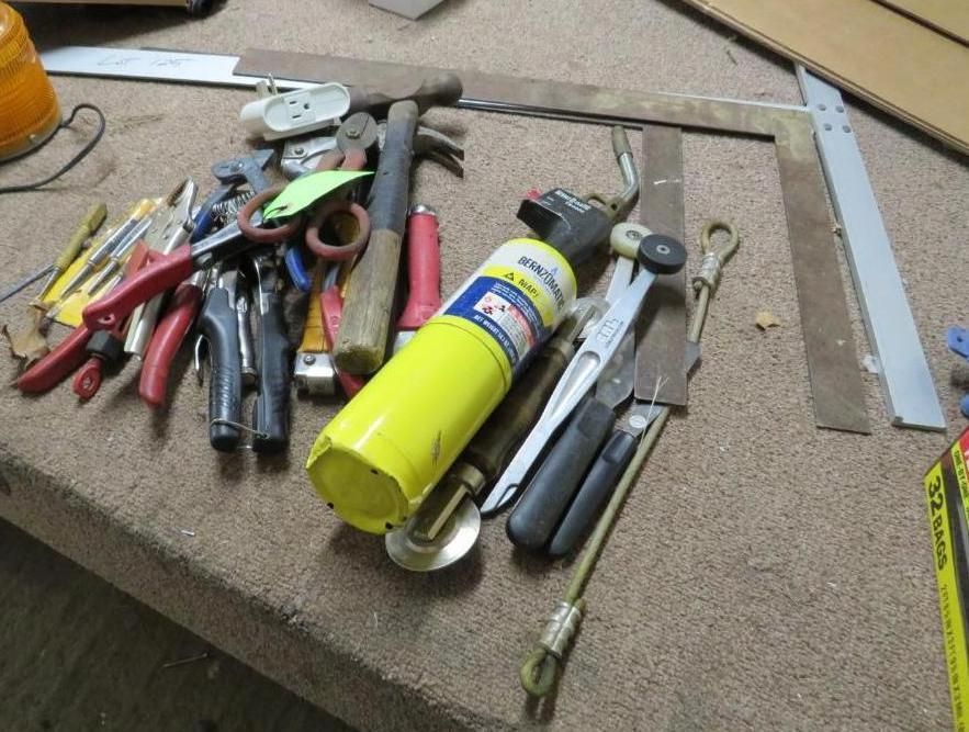 Tools: pliers, hammer, torch, and ruler on a work surface.