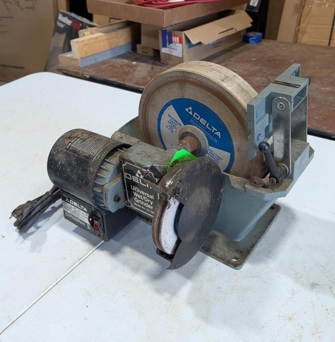 Belt grinder with motor, sanding wheel, and blue abrasive disc on a workbench.