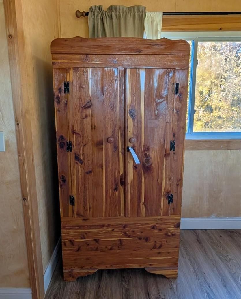 Wooden wardrobe cabinet with dark metal handles in a room beside a window