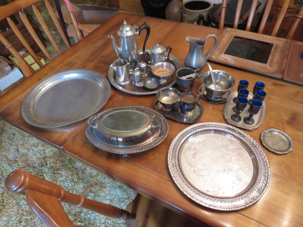 Silver tea service and serving trays arranged on a wooden table.