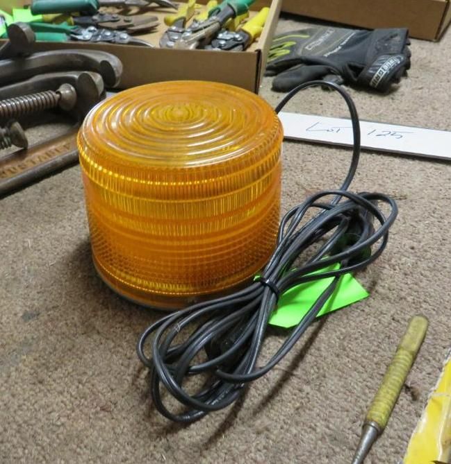 Yellow rotating warning light with a black power cord on a brown surface.