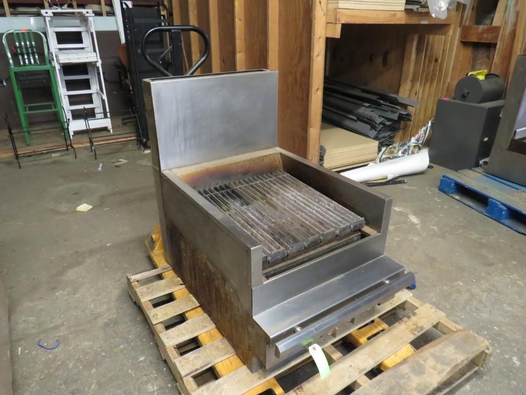 Stainless steel grill on a wooden pallet in a warehouse.