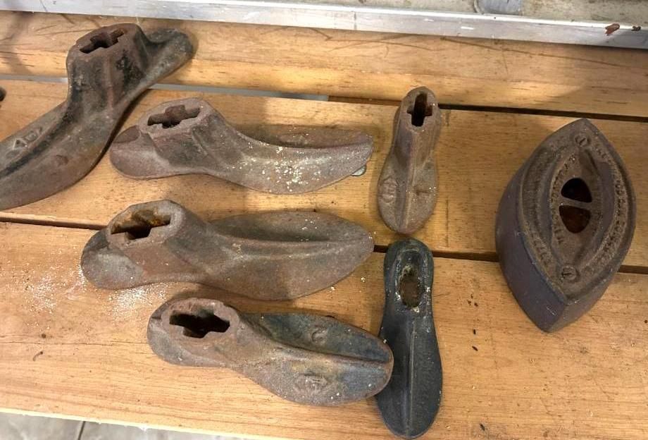 Antique cobbler's tools on a wooden surface: shoe lasts and an iron.