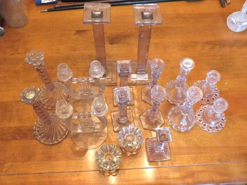 Collection of clear, pressed glass candle holders in various shapes on a wooden surface.
