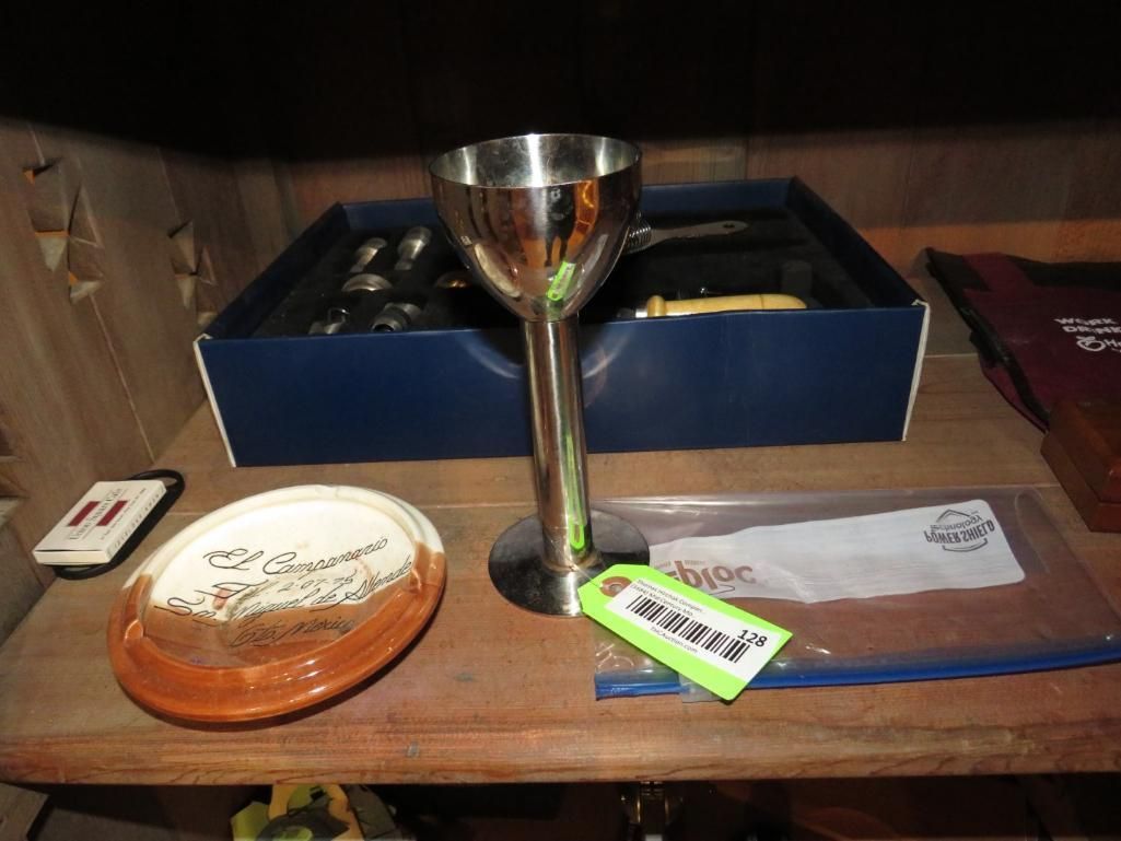 Silver stemmed cup and dish on a wooden shelf, box in the background.