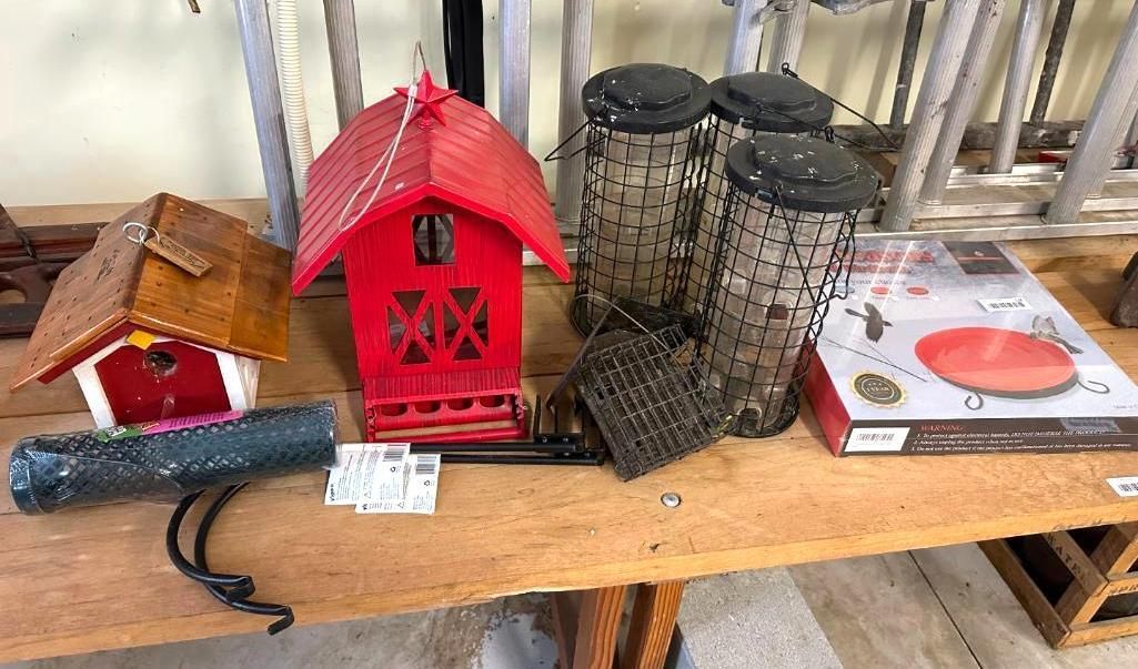Bird feeders of various styles on a wooden table. Red, brown, and clear plastic.