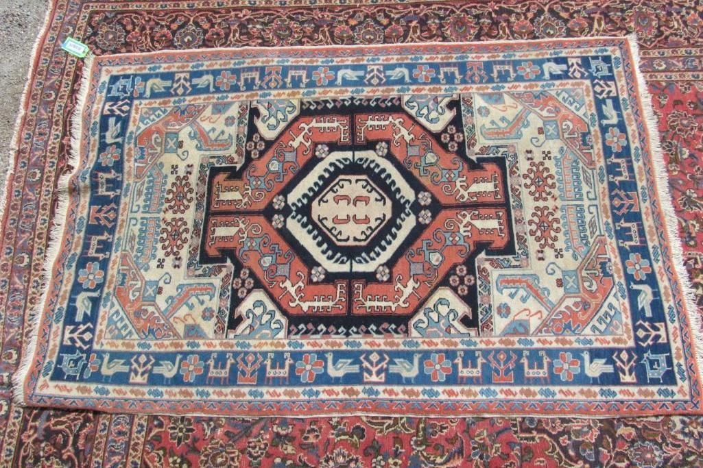 Oriental rug with geometric center design in red, blue, and cream hues.
