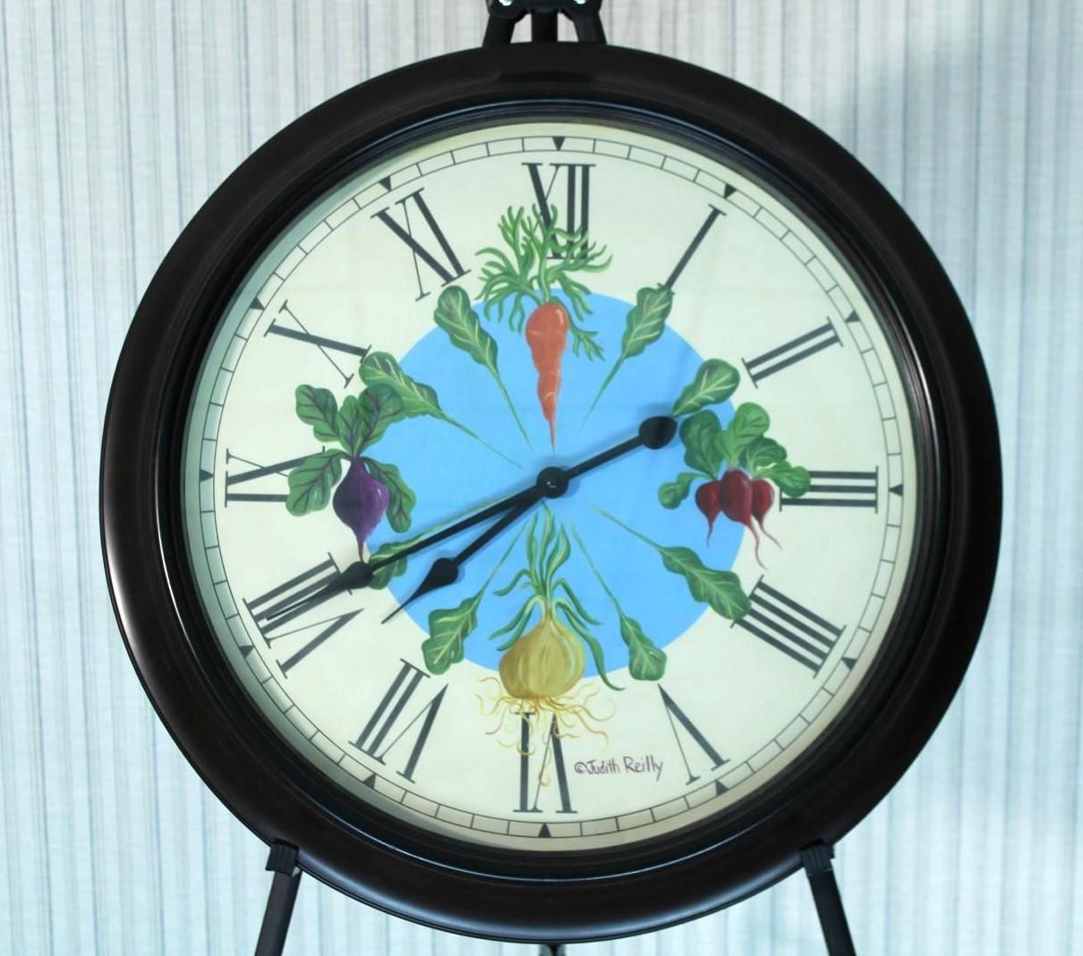 Clock with vegetables painted on the face, set against a blue circle. Dark brown frame, Roman numerals.