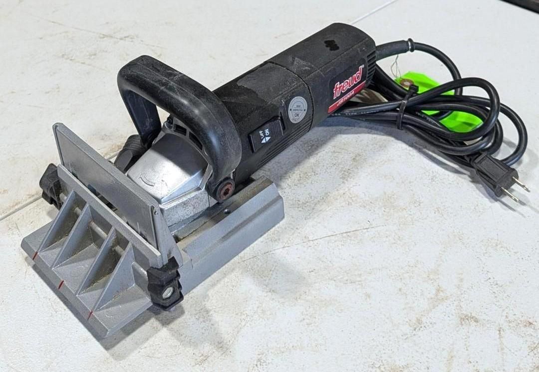 Gray handheld power tool with cord and front guard on a white surface