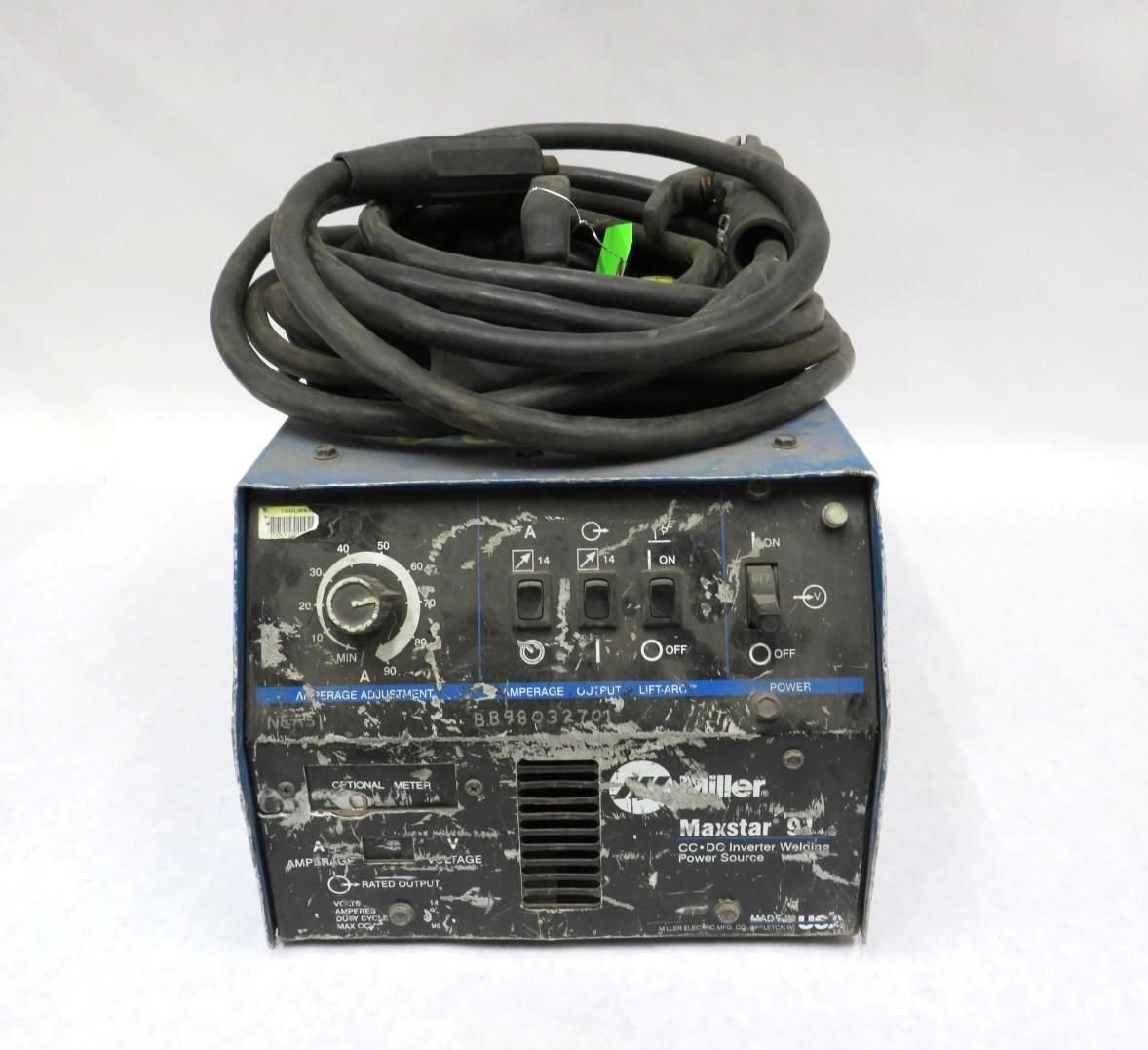 Blue Miller welding machine with black cable coiled on top.