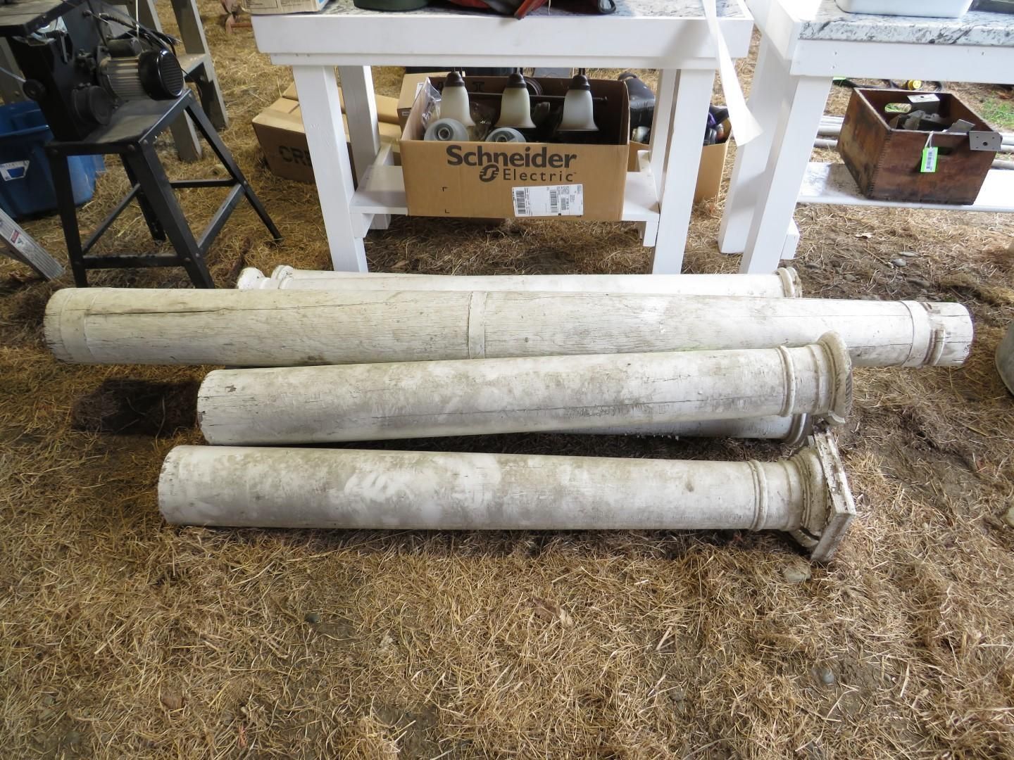Four white concrete columns lying on tan ground.