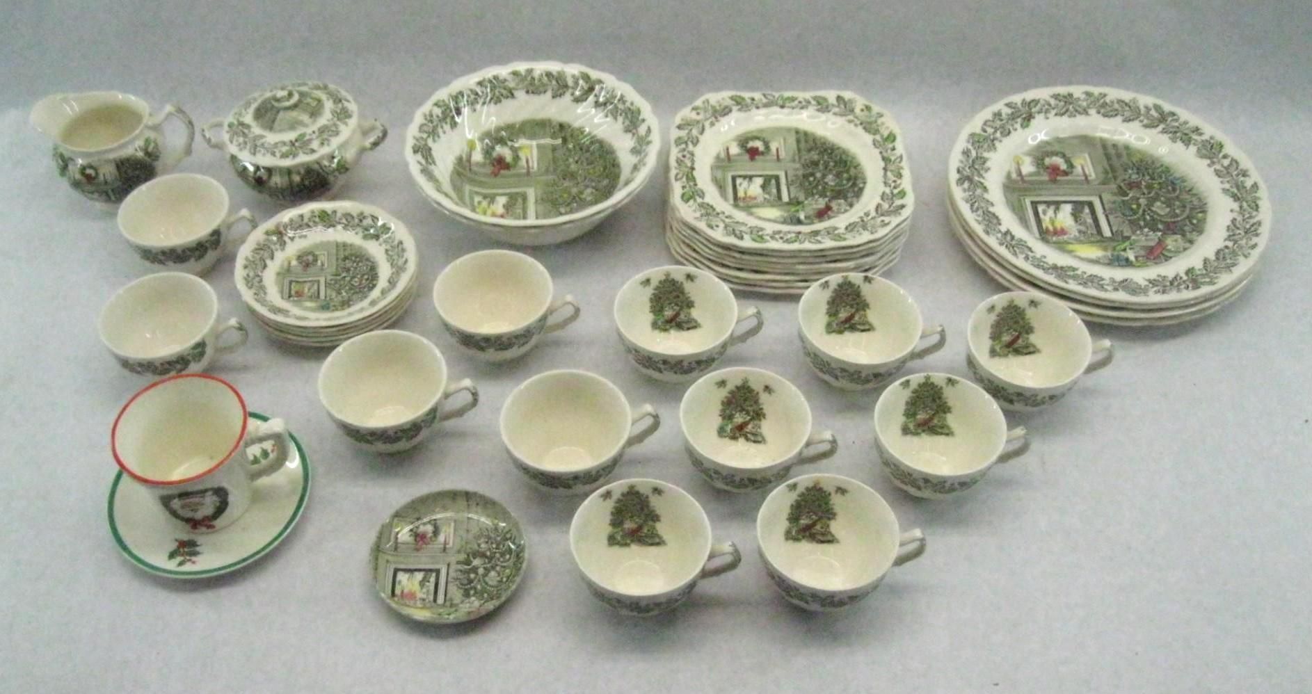 Set of green and white patterned china dishes and teacups arranged on a white surface.