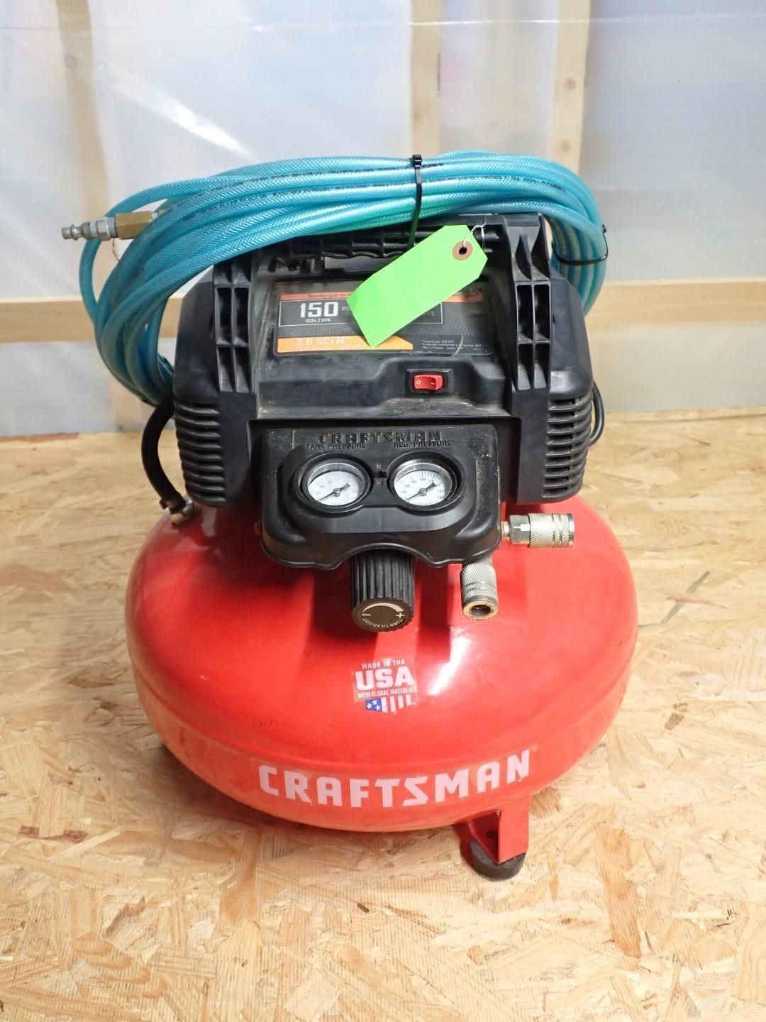 Red Craftsman air compressor with black top, blue hose, and gauges.