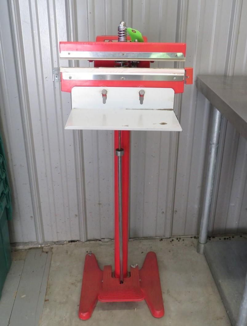Red and white vertical bag sealer on a red stand.