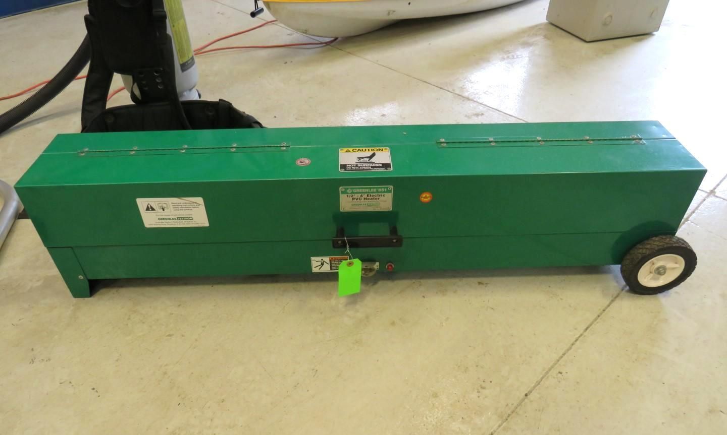 Green rectangular metal tool box with wheels on a floor.
