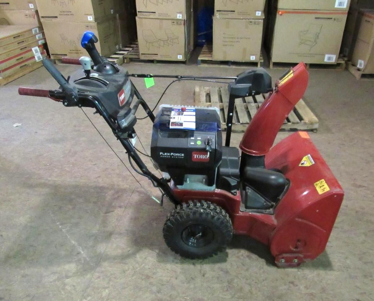 Red and black Toro snowblower on a warehouse floor.