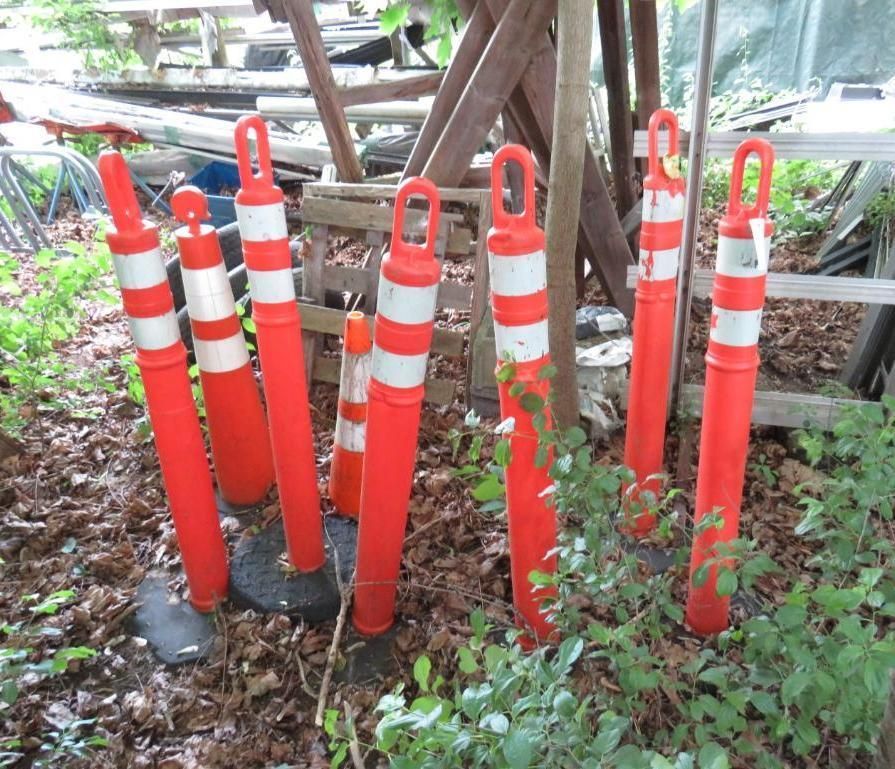 Orange and white traffic cones clustered together outdoors.