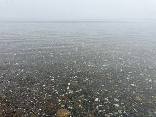 Shallow, clear water over a rocky shore with a hazy horizon in the distance.