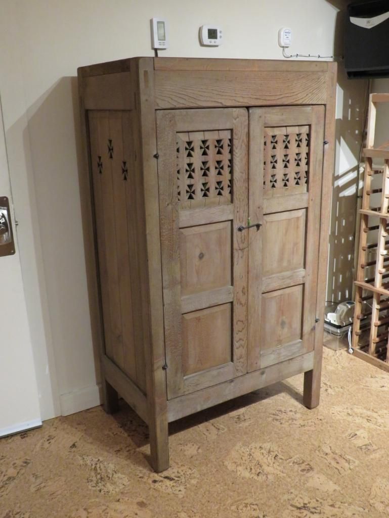 Wooden cabinet with latticed door panels, standing on cork flooring.