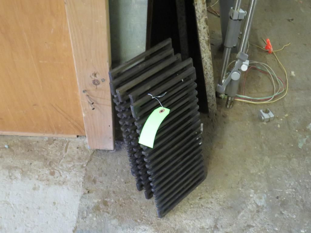 Stack of dark-colored vent covers leaning against a wall, with a green tag attached.