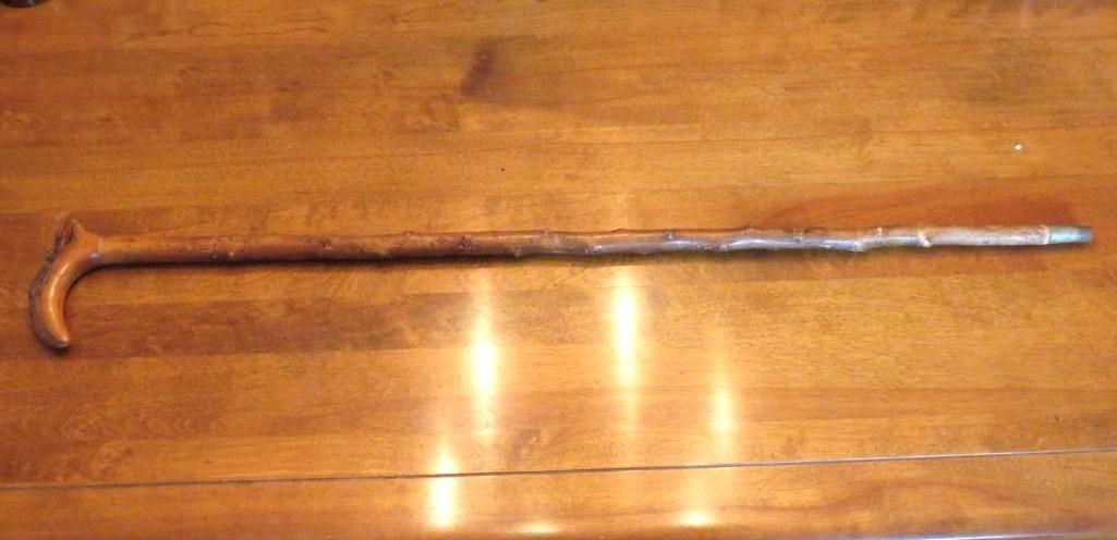 A brown wooden walking cane on a wooden surface.