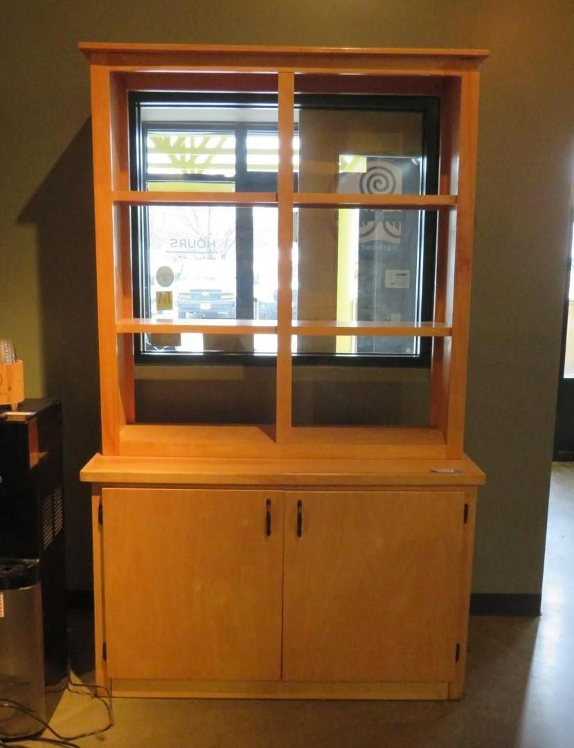 Wooden cabinet with a two-door base and open shelves above, set against a dark wall with a mirror behind the shelves.