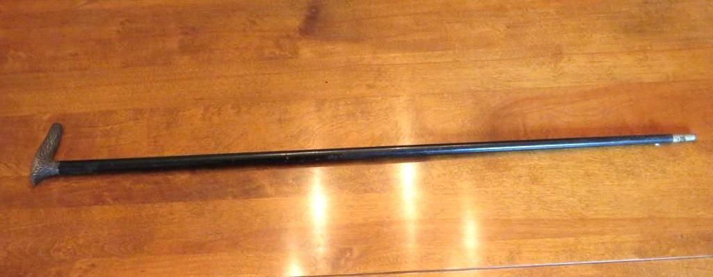 Black walking stick on a wooden surface.