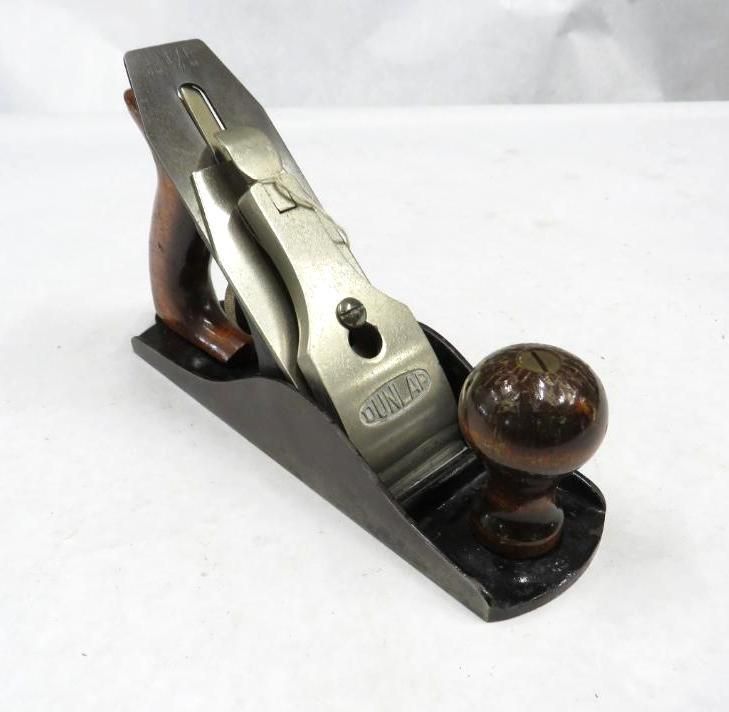 A hand plane, made of wood and metal, sits on a surface. It is used for woodworking.