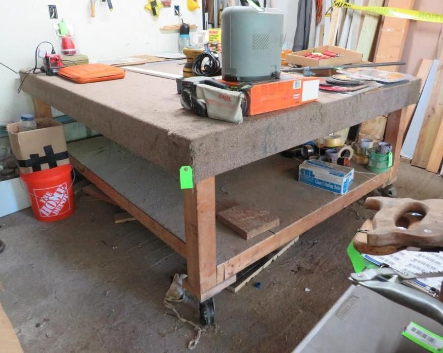 Workbench with tools, supplies, and storage, on a concrete floor in a garage.