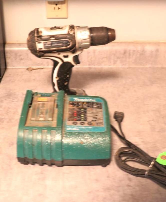 Makita cordless drill and charger on a countertop. The drill is black and silver. The charger is teal.