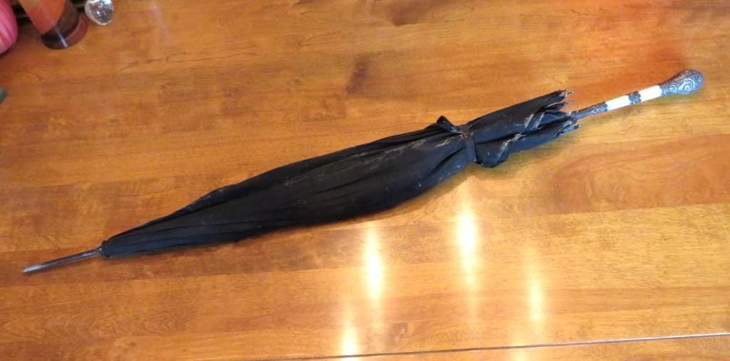 Closed black umbrella on a wooden surface.