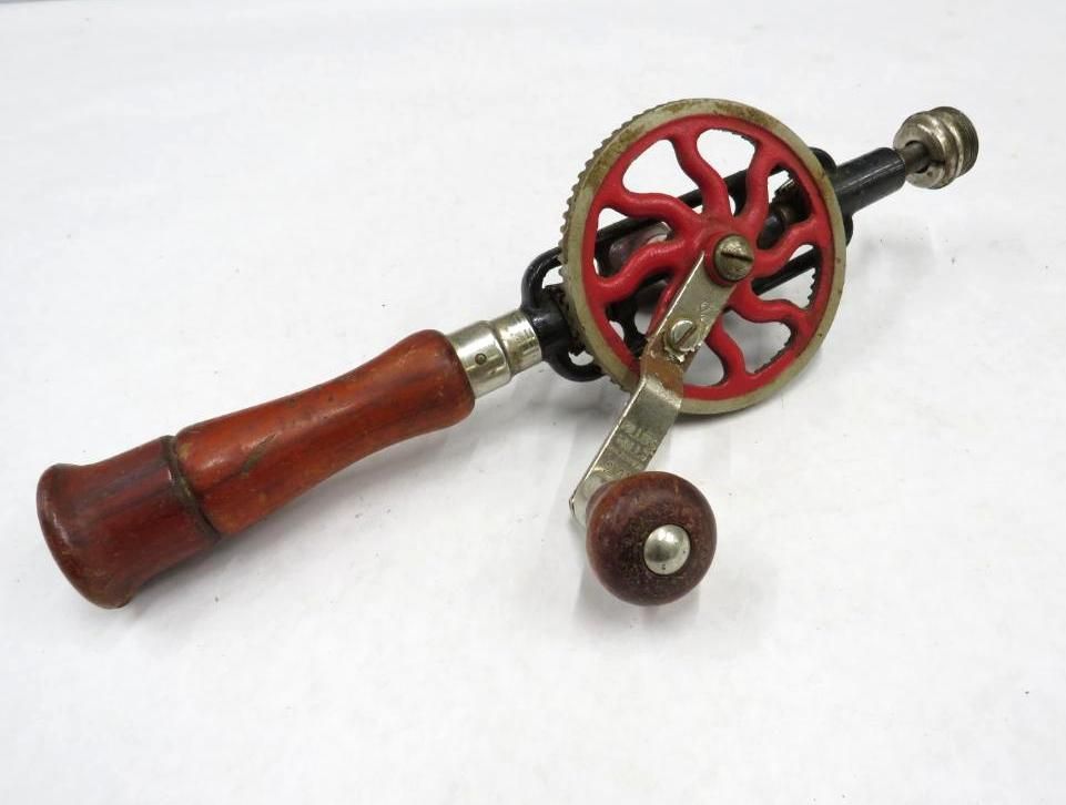 Hand-cranked drill with a wooden handle and red gear.