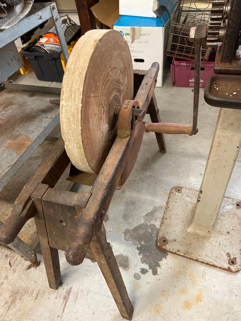 Antique grindstone on a wooden stand, with a hand crank.