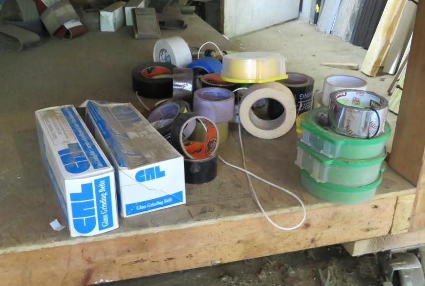 Assortment of tape rolls and boxes on a wooden surface, including electrical and painter's tape.