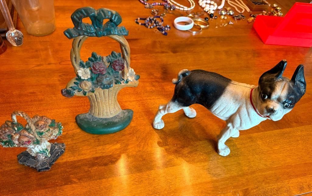 Decorative dog figurine and two floral basket sculptures on a wood surface.