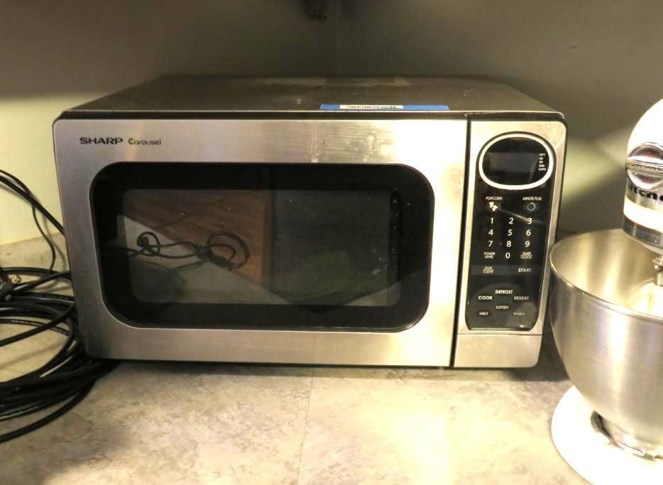 Stainless steel Sharp microwave oven on a counter, with a black control panel and door.