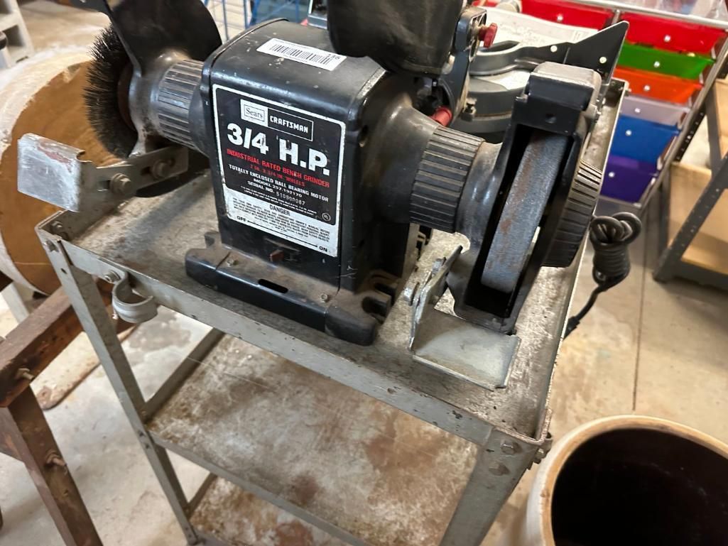 Bench grinder on a metal cart. Black 3/4 HP motor. Brush attachment on one side, grinding wheel on the other.