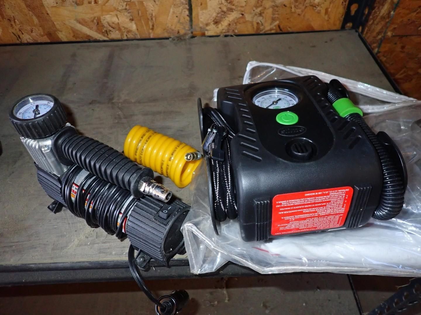 Portable black air compressor with yellow coiled hose and pressure gauge on a workbench