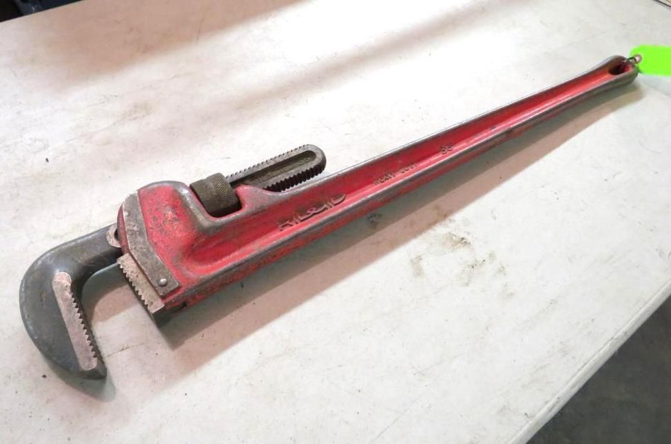 Red pipe wrench on a white surface, ready to grip and turn pipes.