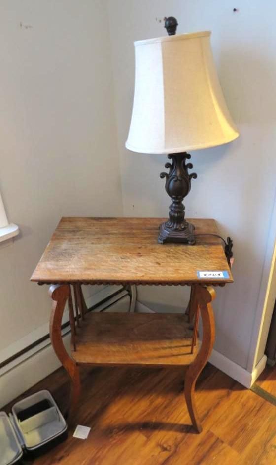 Table with lamp; brown wooden table and lamp, with shade, set against a wall.