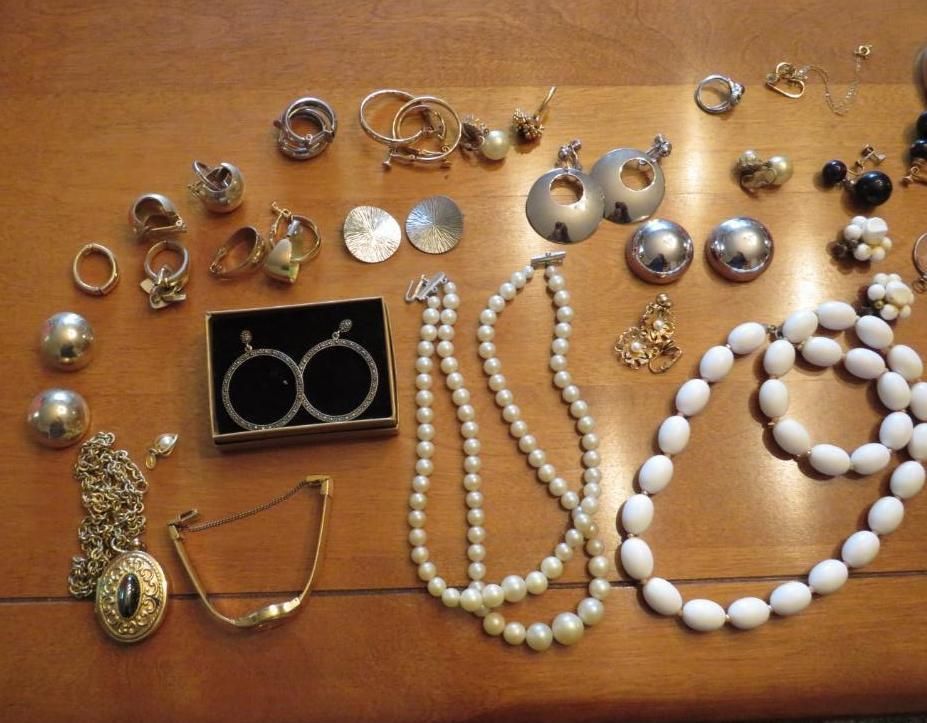 Various pieces of jewelry on a wooden table, including earrings, necklaces, rings, and a bracelet.