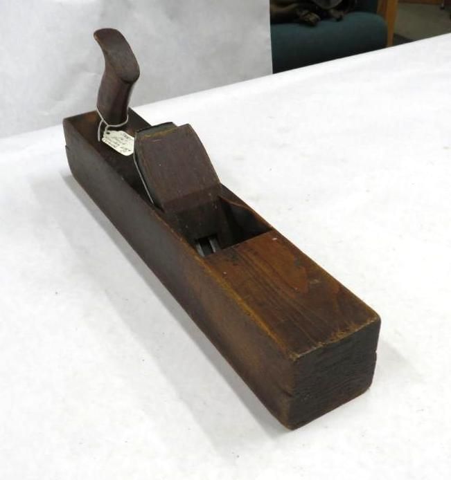 Wooden hand plane on a white surface, dark brown wood, with a handle.
